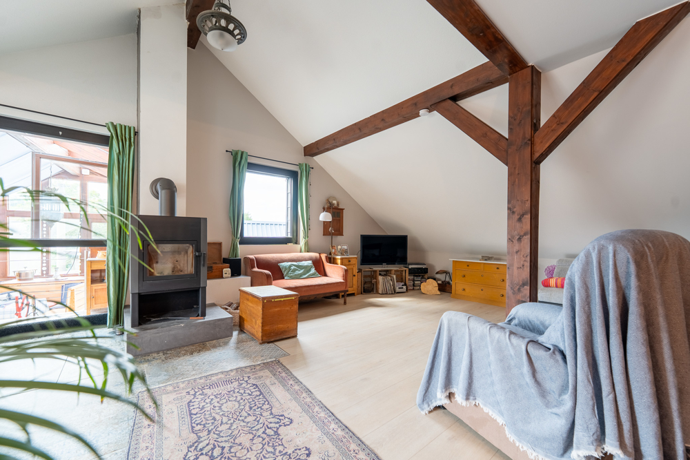 Großer Wohnbereich mit Kamin und Holzbalken